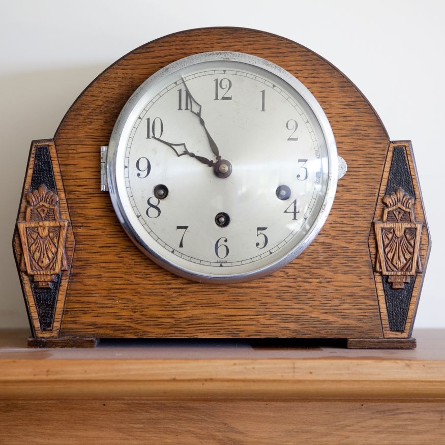 Een standaard antieke klok die staat op de mantel.