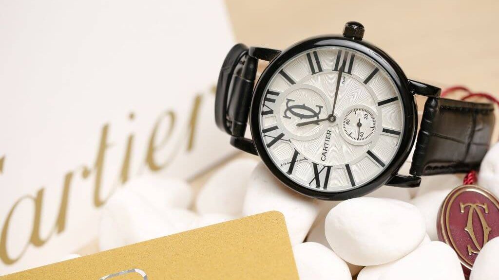 Zwart Cartier horloge met witte wijzerplaat en zwarte, leren band.