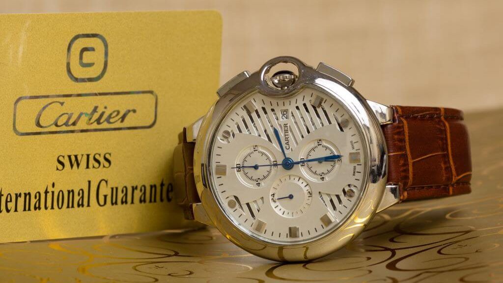 Retro Cartier horloge met stalen kast, wite wijzerplaat en bruin, leren band. Samen met gele garantiebewijs van Cartier.