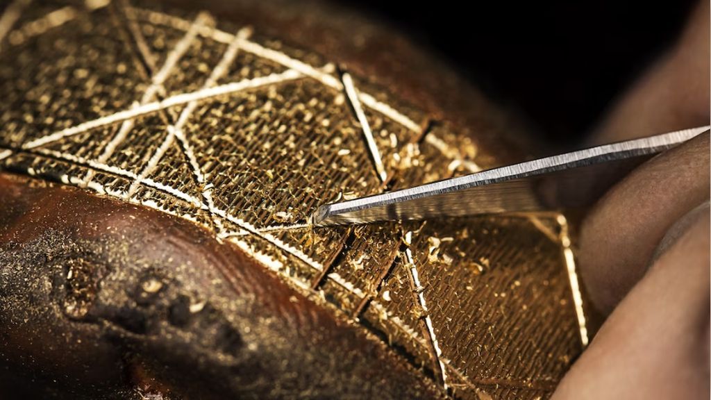 Geelgouden Christian Dior horlogeband die met de een smal gereedschap met de hand gegraveerd wordt door een goudsmid.
