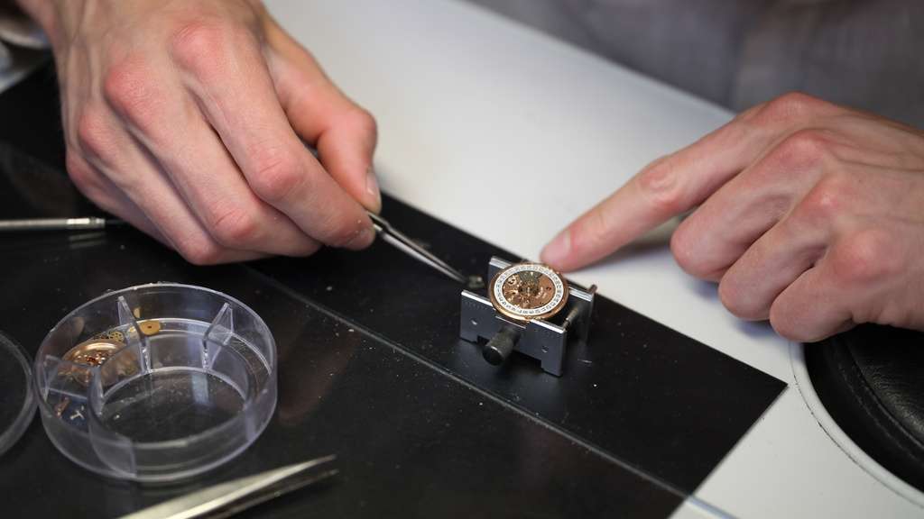 Horlogemaker repareert uurwerk van Breitling horloge met pincet.