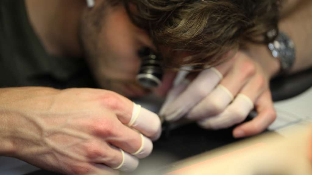 Horlogemaker met loep bezig om een Breitling uurwerk te repareren.