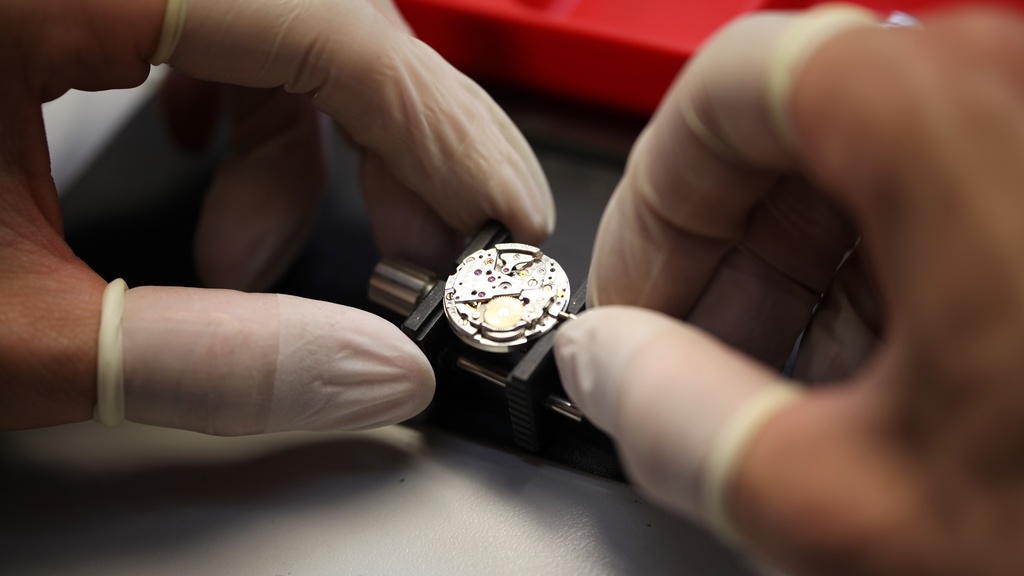 Uurwerk van Montblanc horloge wordt gerepareerd door horlogemaker met handschoenen aan.