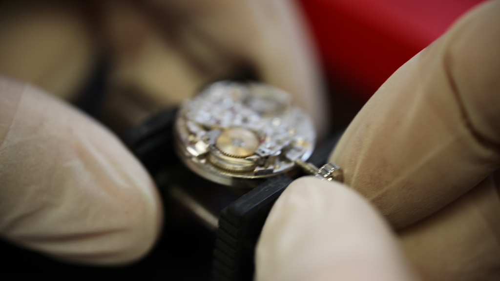 Horlogemaker beweegt kroon van Armani horloge met handschoenen aan.