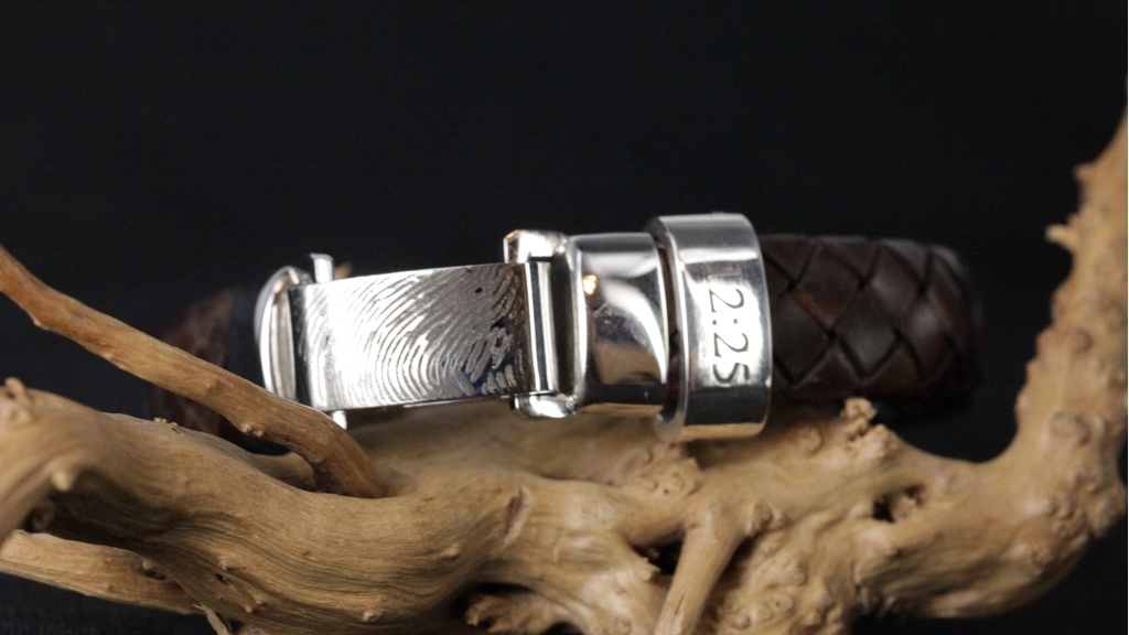Leren armband met zilveren aplic met gravure datum en slot gravure met vingerafdruk op houten tak.