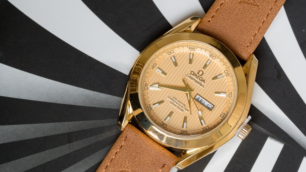 Omega Seamaster, een bijzonder horloge met geelgouden kast, beige wijzerplaat en bruin leren band.