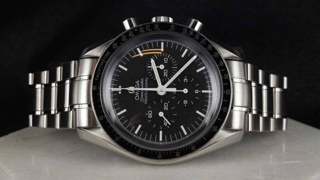 Omega stalen horloge met zwarte wijzerplaat en lunette die op zijn kant ligt op een marmeren, witte ondergrond.