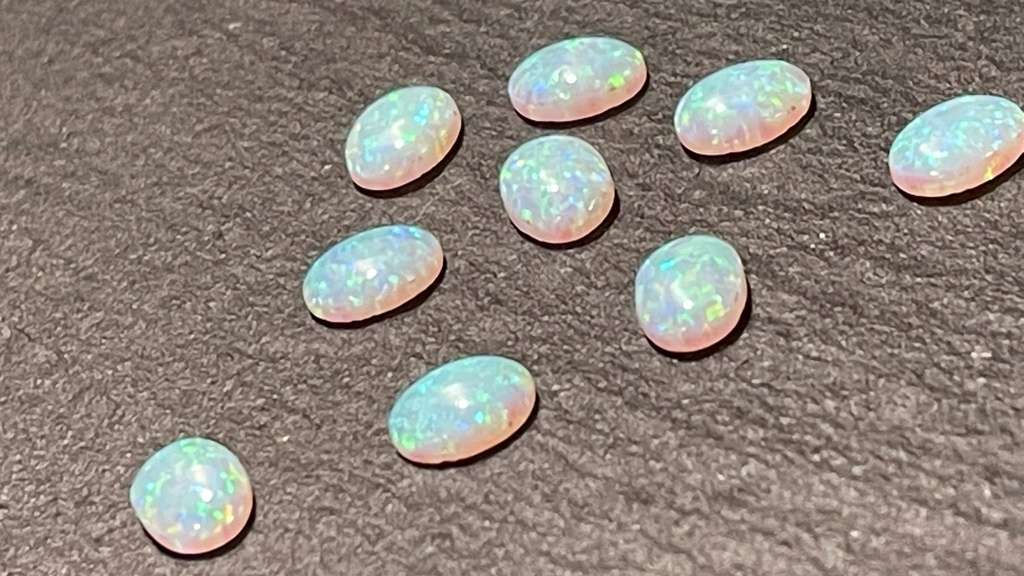 9 Opaal stenen in ronde vorm op stenen ondergrond.