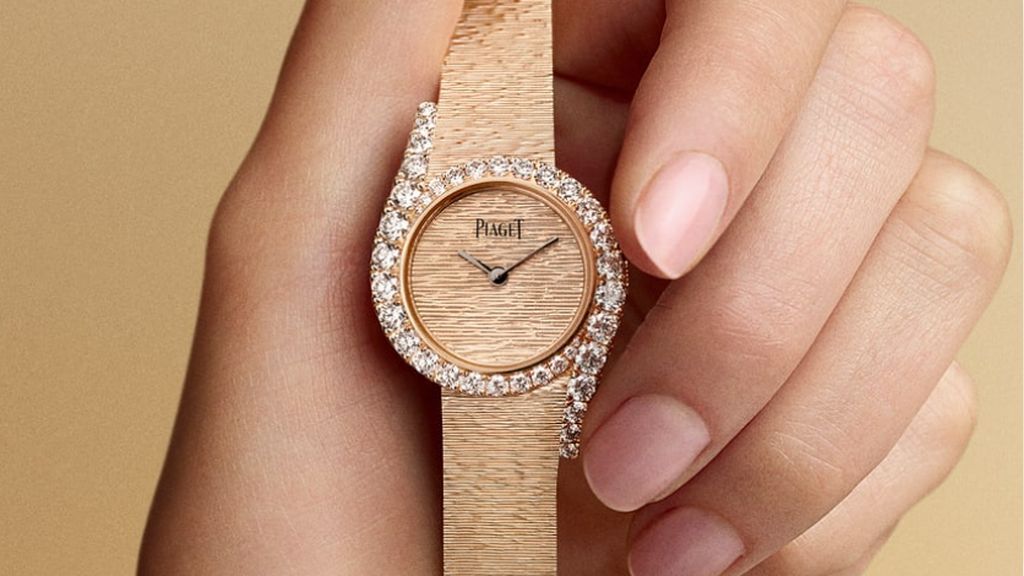 Limelight Gala Precious watch horloge roségoud met briljanten in lunette wordt vastgehouden door hand op beige achtergrond.<br />
