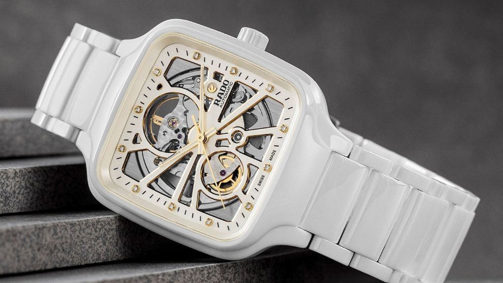 Wit keramieken Rado horloge met zichtbaar uurwerk als wijzerplaat, schuin liggend op grijze trap.