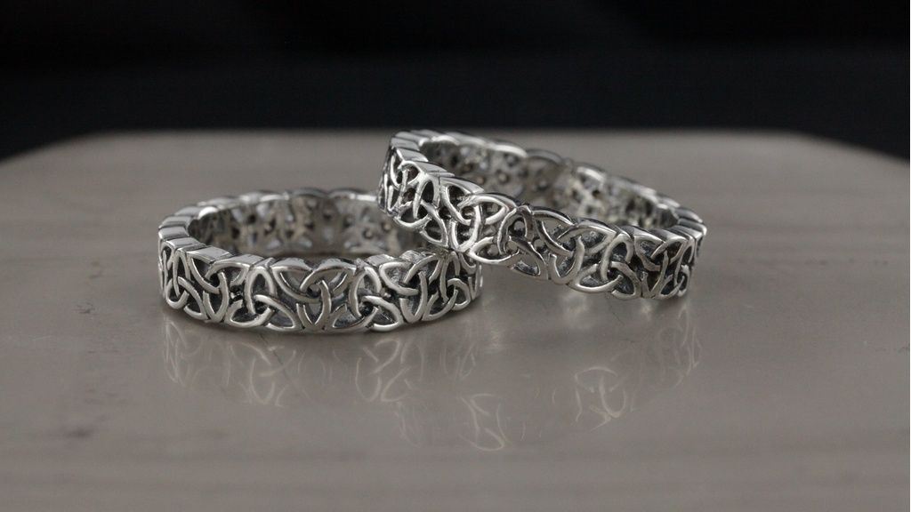 Set zelf ontworpen zilveren ringen met open gevlochten patroon op effen grijze ondergrond en zwarte achtergrond.