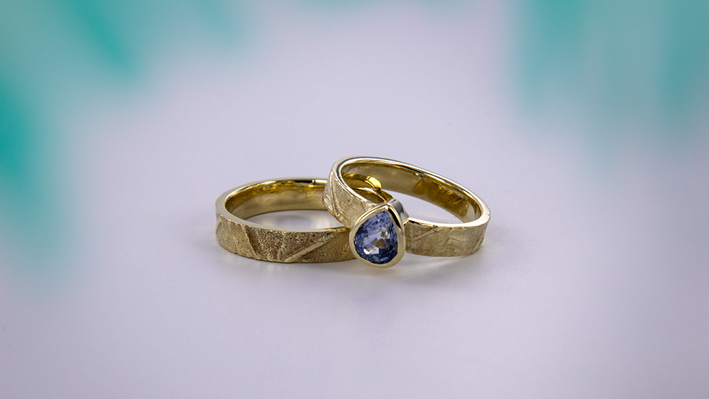 Trouwringen op maat laten maken zoals deze set geelgouden trouwringen uit de volcano collectie met blauwe diamant