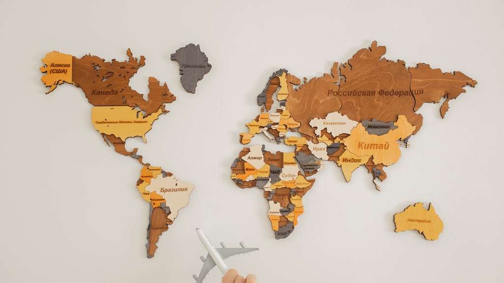 Wereldkaart met oranje, bruine en grijze kleuren met Australië in oranje met hand die vliegtuig vasthoudt