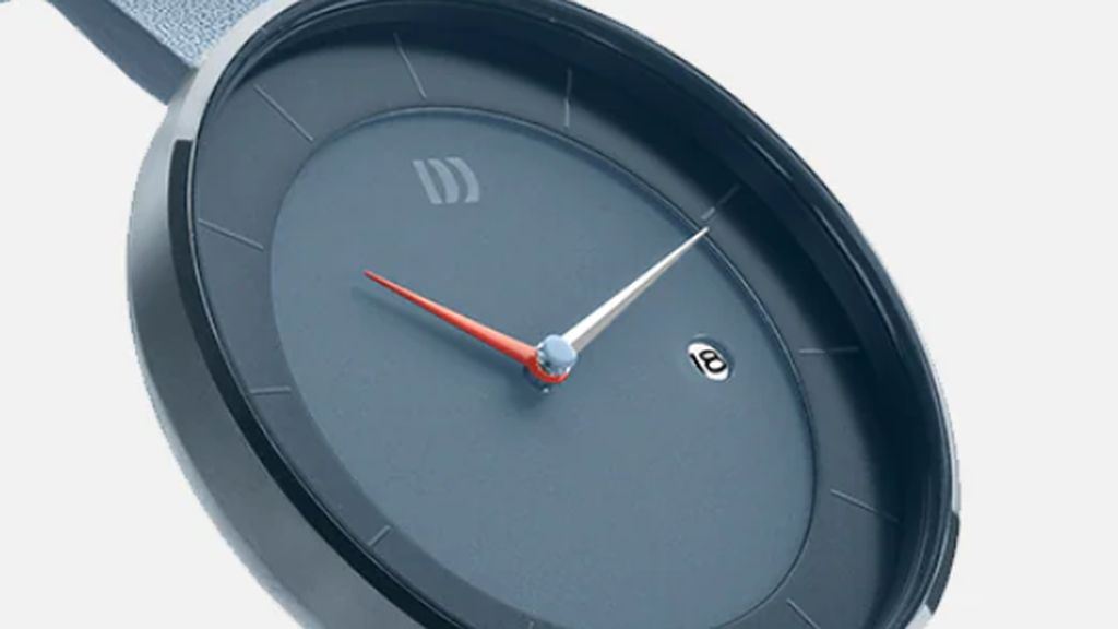 Blauw Danish Design horloge met blauwe kast, blauwe rubberen band en blauwe wijzerplaat met rode en witte wijzers op witte achtergrond.