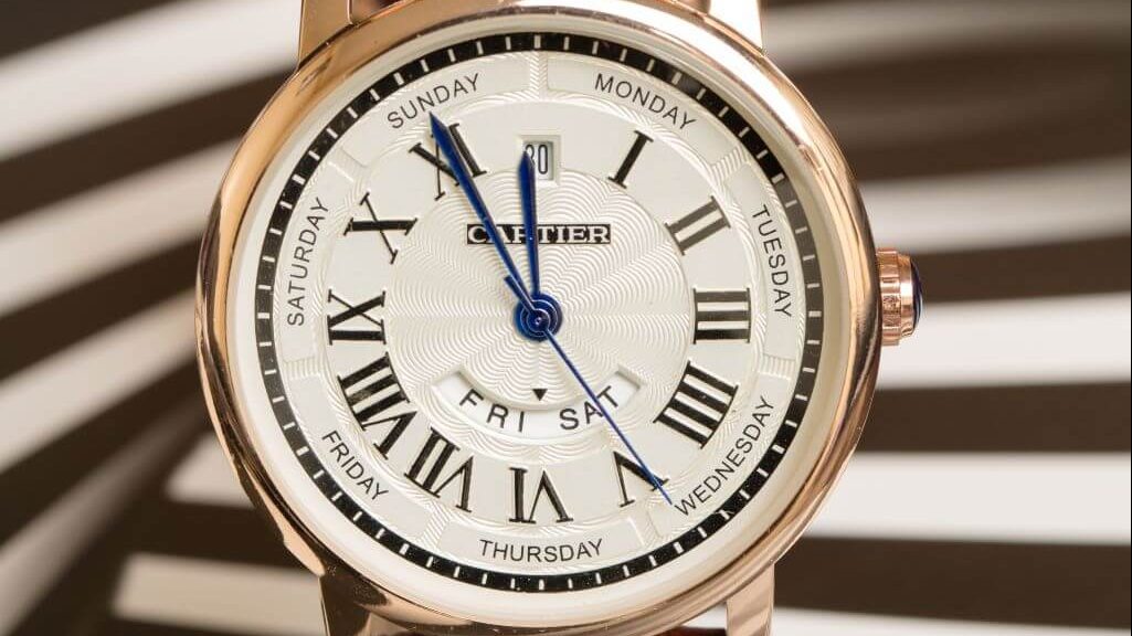 Roségouden Cartier horloge met witte wijzerplaat, zwarte romeinse cijfers en een blauwe secondewijzer.