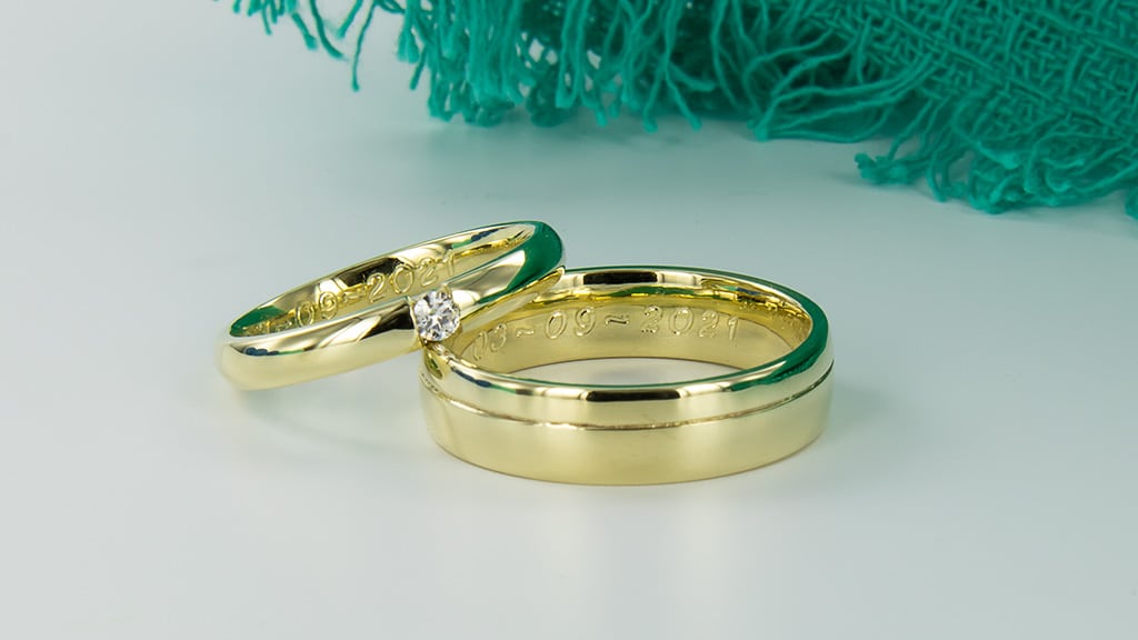 Set geelgouden trouwringen met diamant damesring en beide een diamantstiftgravure van de trouwdatum